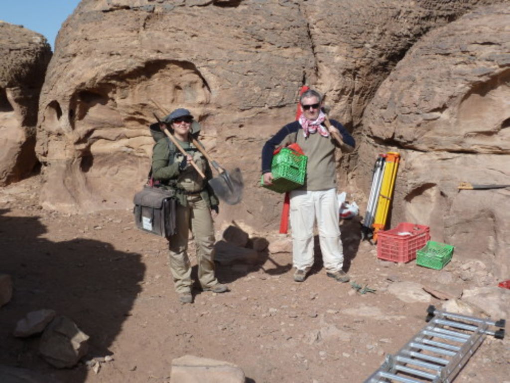 Fig. 10: Polly Agoridou in her jungle assault outfit and André Barmasse picking up their digging equipment in front of the camp site.